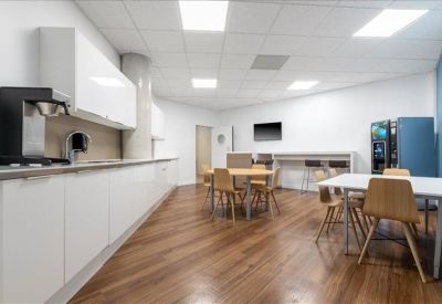 Spacious communal kitchen and dining area with wood-style flooring and natural light.
