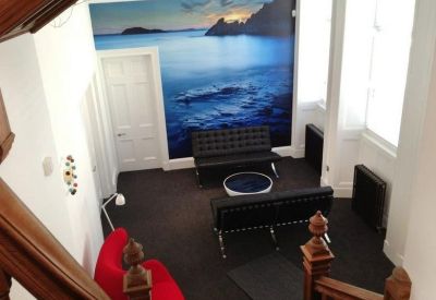 Breakout lounge with black sofas and a scenic coastal wall graphic.