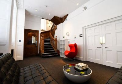 Reception area featuring a red egg chair and a striking wooden staircase.