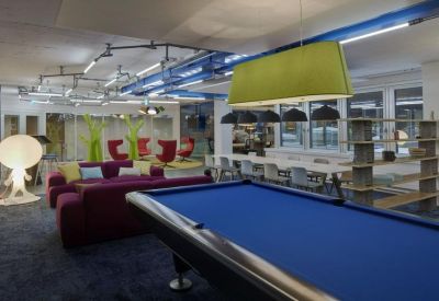 Spacious breakout area featuring a blue pool table, purple sofas, and a large lime green pendant lamp.