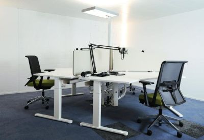 Modern white height-adjustable desks with black ergonomic chairs and a podcast microphone setup.