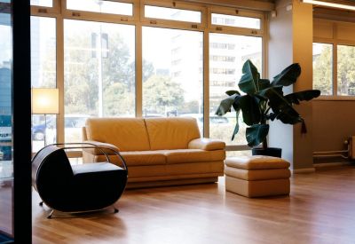 Bright office breakout space with comfortable leather seating and floor-to-ceiling windows.