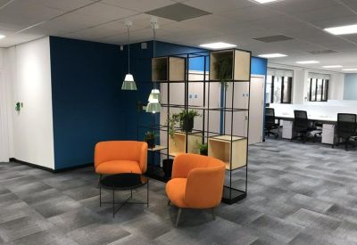 Breakout area with orange armchairs, a blue feature wall, and modern shelving.