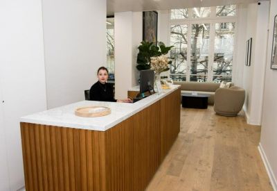 Reception area featuring a wooden slatted desk and a view into a bright lounge.