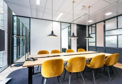 Modern conference room with a light wood table, vibrant yellow chairs, and stylish black pendant lights.