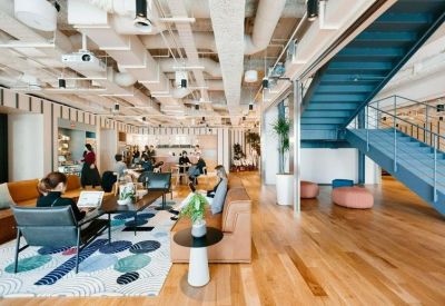 Bright open-plan lounge with a blue staircase and industrial ceilings.