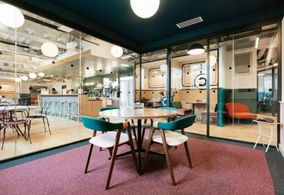 Modern meeting table on a pink rug with views into an adjacent cafe.