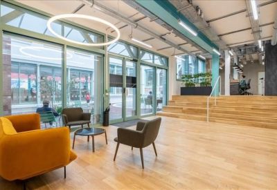 Spacious lounge area with wood floors, yellow armchairs, and large glass doors leading to a courtyard.