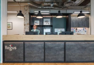 Modern reception desk with dark textured panels and a illuminated company logo.