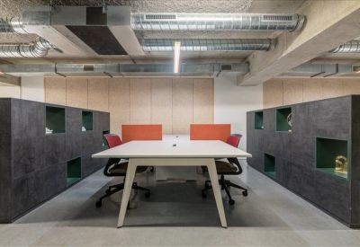 Symmetrical coworking space with white desks, orange privacy screens, and exposed ceiling ductwork.