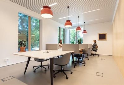 Vibrant communal workspace featuring red pendant lights, wooden accents, and green plants.
