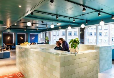 Coworking lounge with a large tiled central counter and modern hanging globe lights.