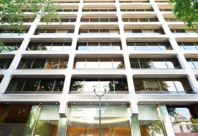 Ground level view of the modern glass entrance and white tiered facade of Avenue Louise 235.