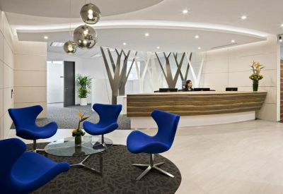 Reception lobby featuring bright blue egg chairs and a curved wood-panelled desk.