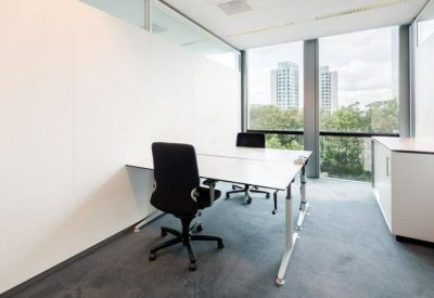 Minimalist private office suite with white desks and views of city greenery.