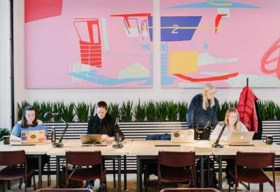 Shared workspace featuring communal desks, task lamps, and vibrant pink wall art.