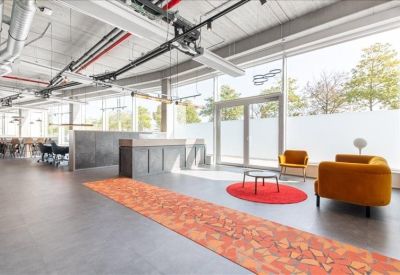 Modern open-plan communal area with a reception counter and colorful orange rug.