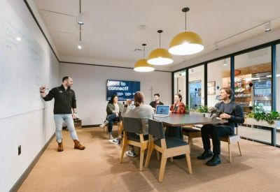 Professional meeting room with a large table, yellow pendant lights, and a white board.