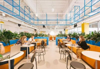 Vibrant coworking space with orange banquette seating, blue partitions, and indoor plants.