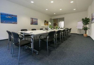 Large professional boardroom with a long white table and black chairs.