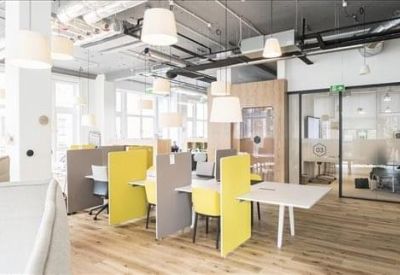 Bright open-plan office with yellow partitioned desks and glass-walled meeting rooms.