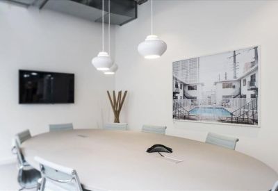 Modern meeting room featuring a large oval table, white pendant lights, and a wall-mounted TV.