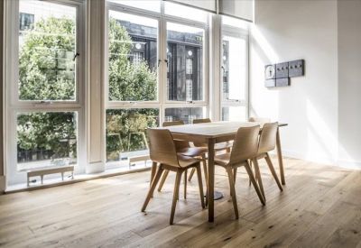 Sunny break area with a wooden dining table and large windows overlooking greenery.