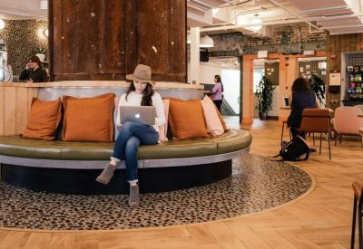 Circular built-in seating area with orange cushions surrounding a wooden structural pillar.