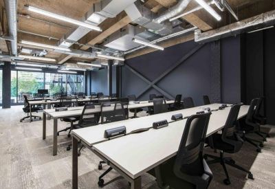 Professional open-plan office with rows of white desks and ergonomic black chairs.