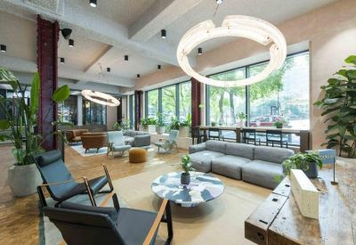 Spacious lounge with a large circular light fixture, grey sofas, and floor-to-ceiling windows.