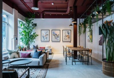 Industrial-style breakout area with dark red ceilings, dining tables, and potted greenery.