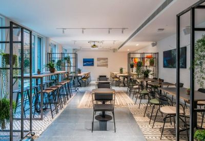 Open-plan coworking space with long wooden tables, stools, and framed artwork.