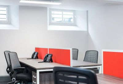 Bright office space with white walls and desks separated by red privacy screens.