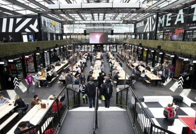 Spacious communal dining hall and coworking hub with long wooden tables and black and white decor.