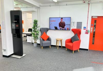 Modern breakout area with grey and red wingback chairs and a bright red door.