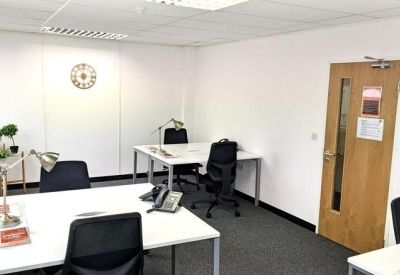 Bright private office suite with white desks and a wall-mounted clock.