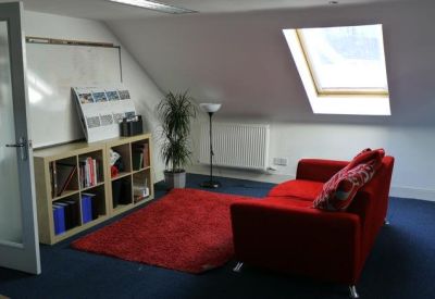 Attic office area featuring a red sofa, bookshelf, and large skylight window.