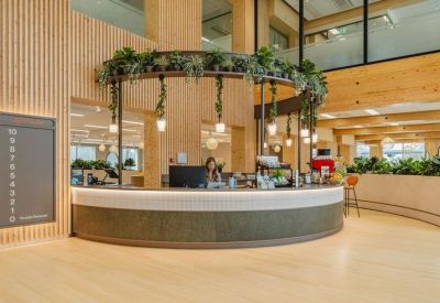 Modern reception desk with a circular overhead planter and warm wood paneling.
