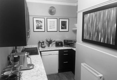 Compact kitchen area featuring a marble-effect countertop and monochrome artwork.