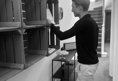 A hallway with rustic wooden crates used as shelving and a staircase in the background.