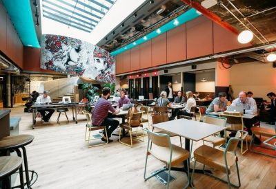 Large open-plan cafe area with skylights, colorful mural, and numerous dining tables.