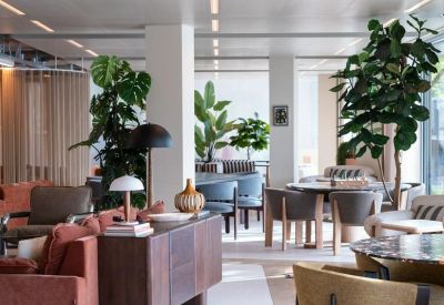 Spacious communal lounge featuring velvet seating and large indoor plants.