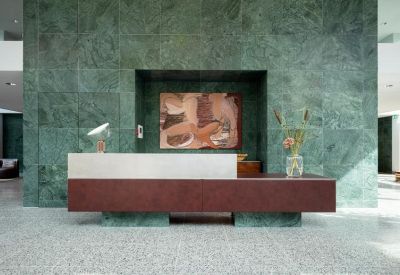 Minimalist reception area with a green marble wall and wooden desk.