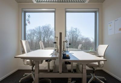 Bright two-person office suite with sit-stand desks and tree-lined views.