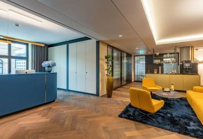 Modern reception area with a blue desk, yellow armchairs, and herringbone wood floors.