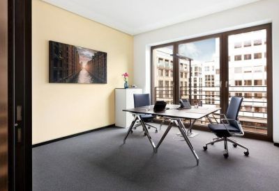 Bright private office with two workstations and views of neighboring classical architecture.