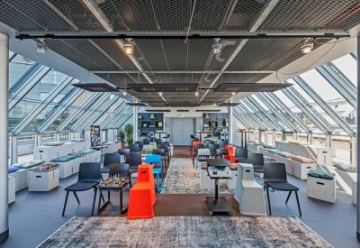 Spacious top-floor communal area with eclectic seating under a glass-slanted roof.