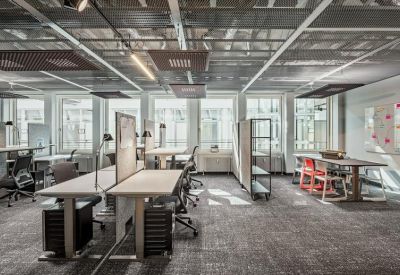 Industrial style open-plan office with exposed ceilings and multiple workstations.