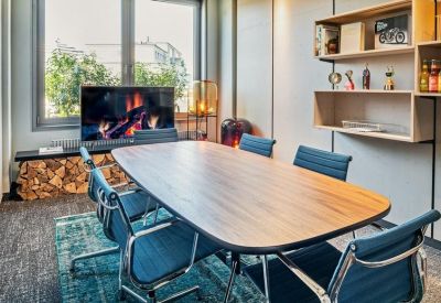 Cozy meeting room with a wooden table, blue chairs, and a digital fireplace display.