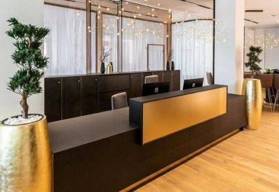 Elegant black reception desk with a gold accent panel and decorative trees.